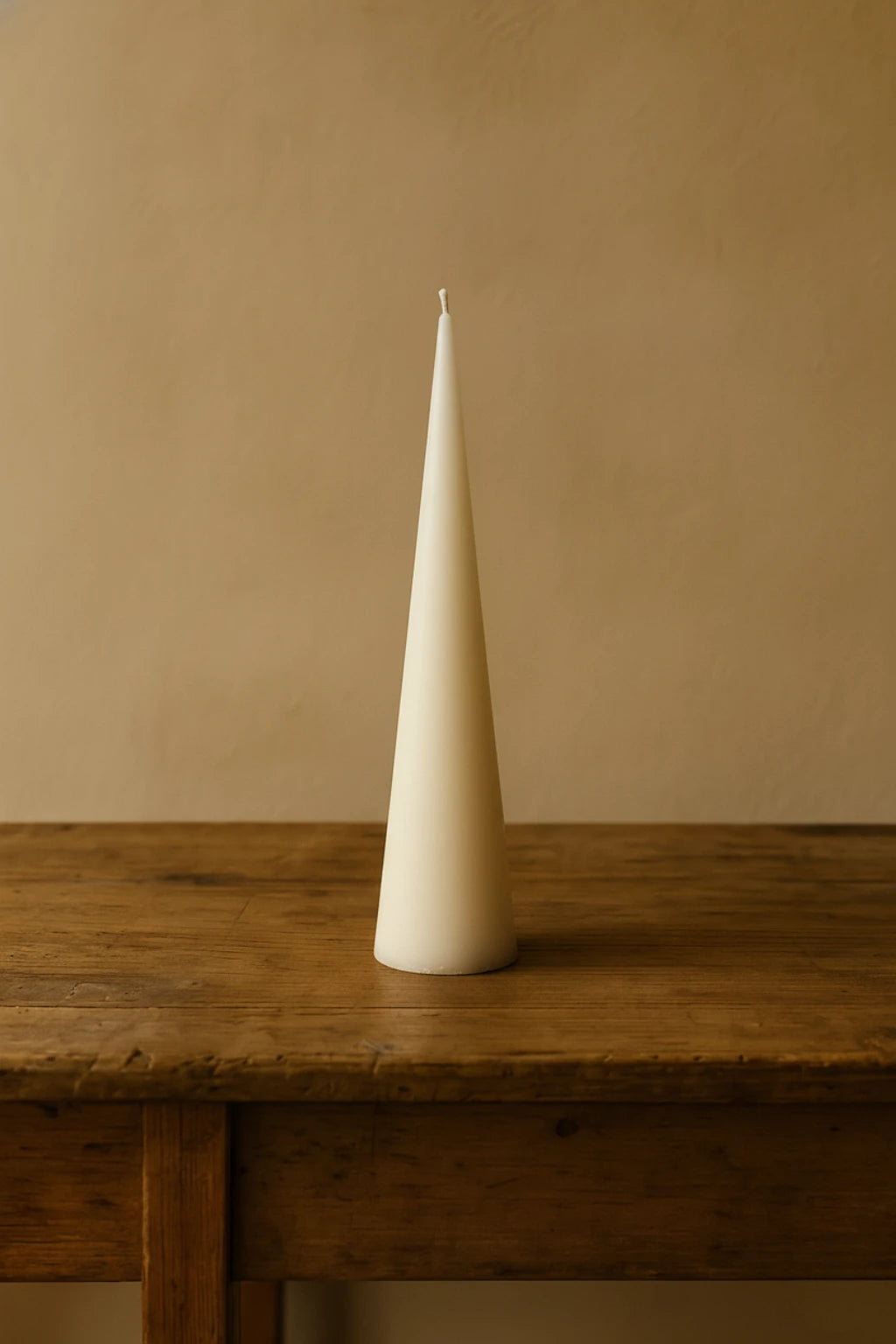 Grankoglen bivokslys i råhvid fra Persillo, håndlavet i 100% bivoks, stående slukket på træbord mod neutral baggrund.