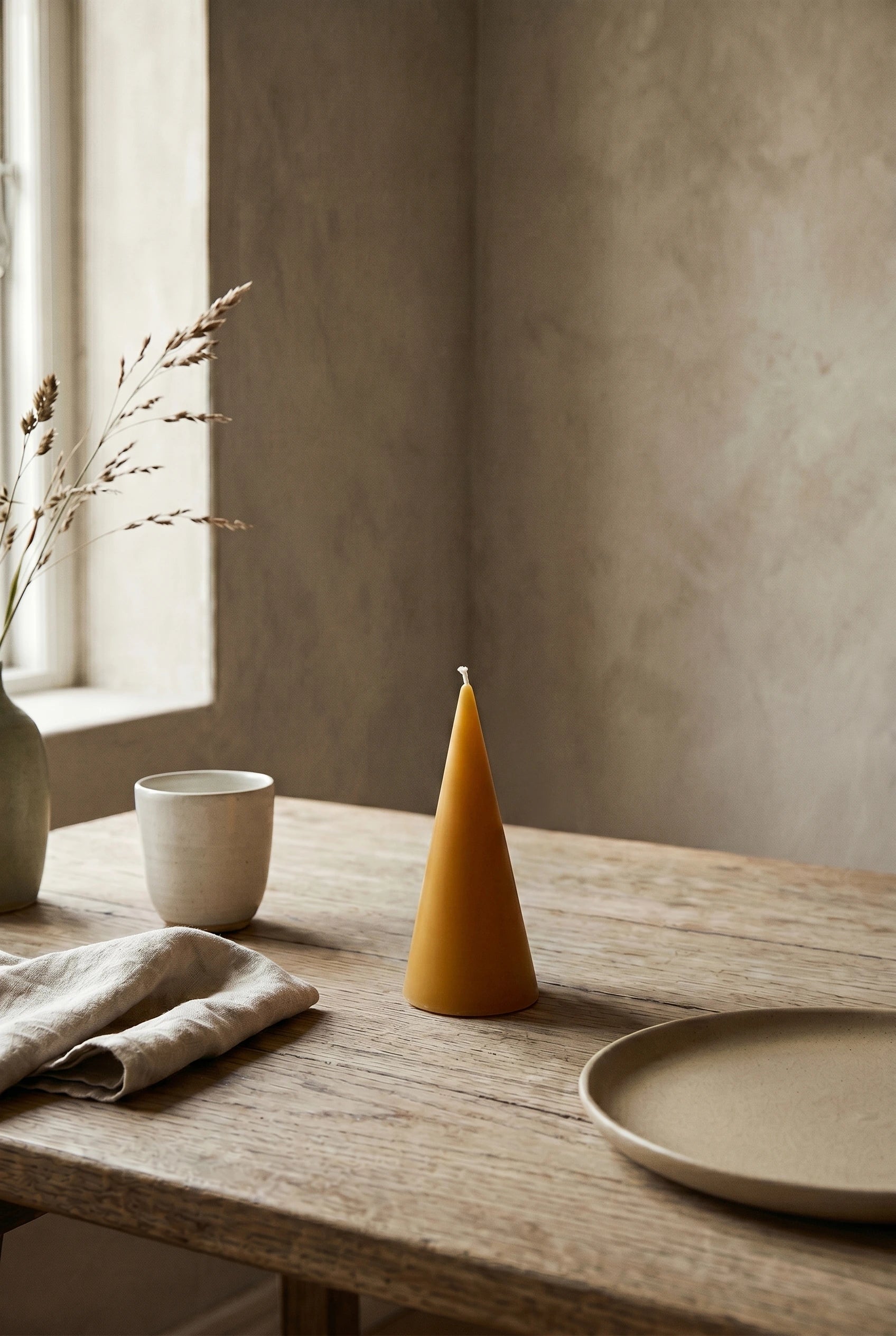 Persillo Koglen Gylden bivokslys på moderne scandi spisebord med stentøj og linned